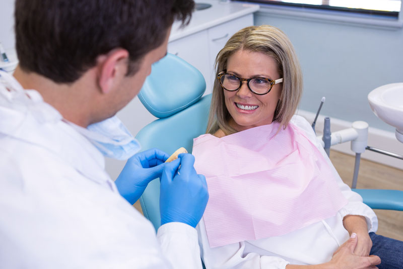 mature woman talking to dentist about implant options