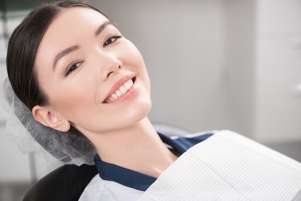 Very nice lady with dark hair smiling in dental chair
